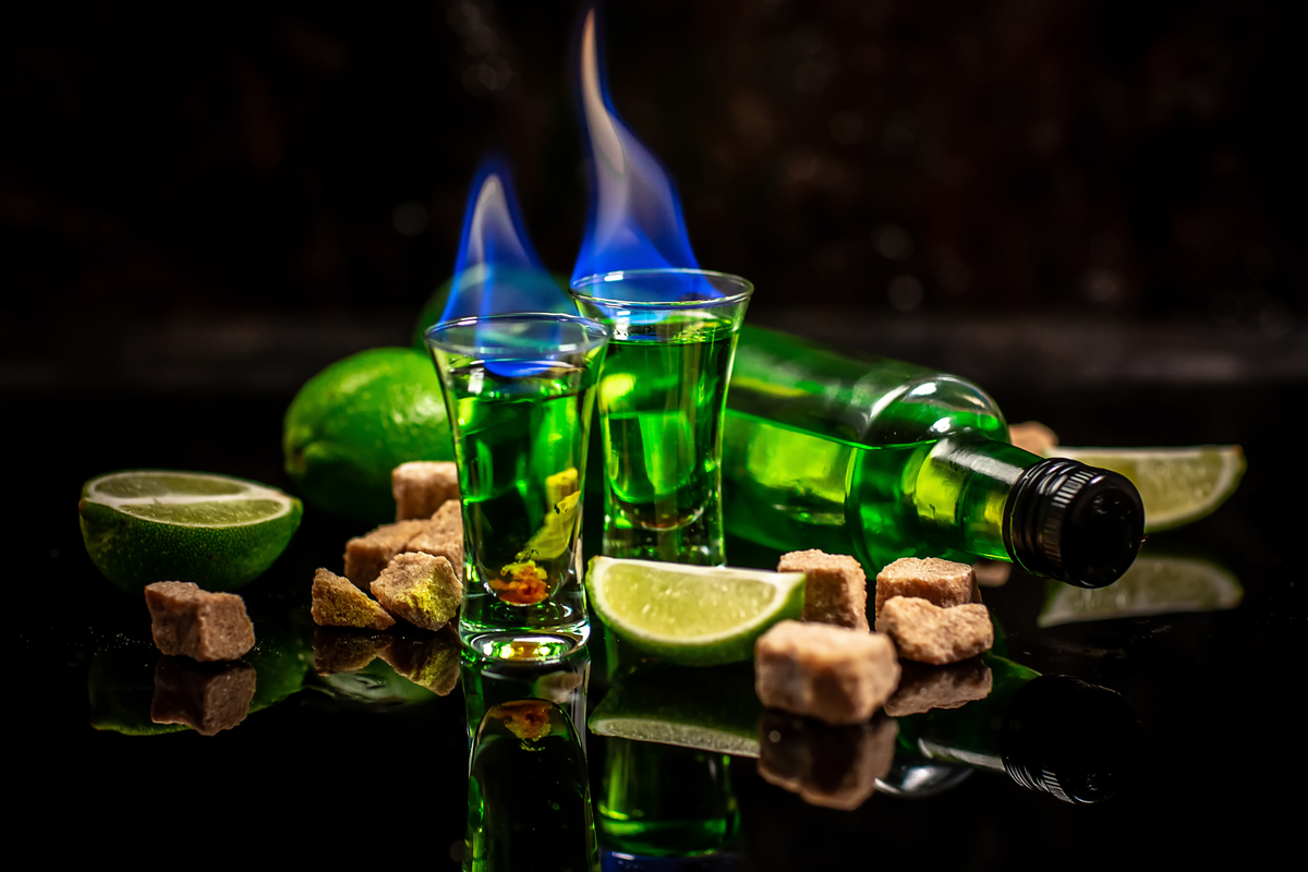 absinthe shots with sugar cubes. absinthe poured into a glass. bottle of absinthe with brown sugar and lime isolated on black background. space for text